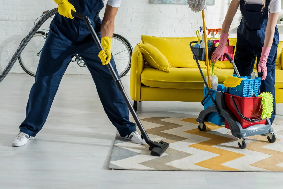 Reinigungsteam saugt Teppich und reinigt Wohnung
